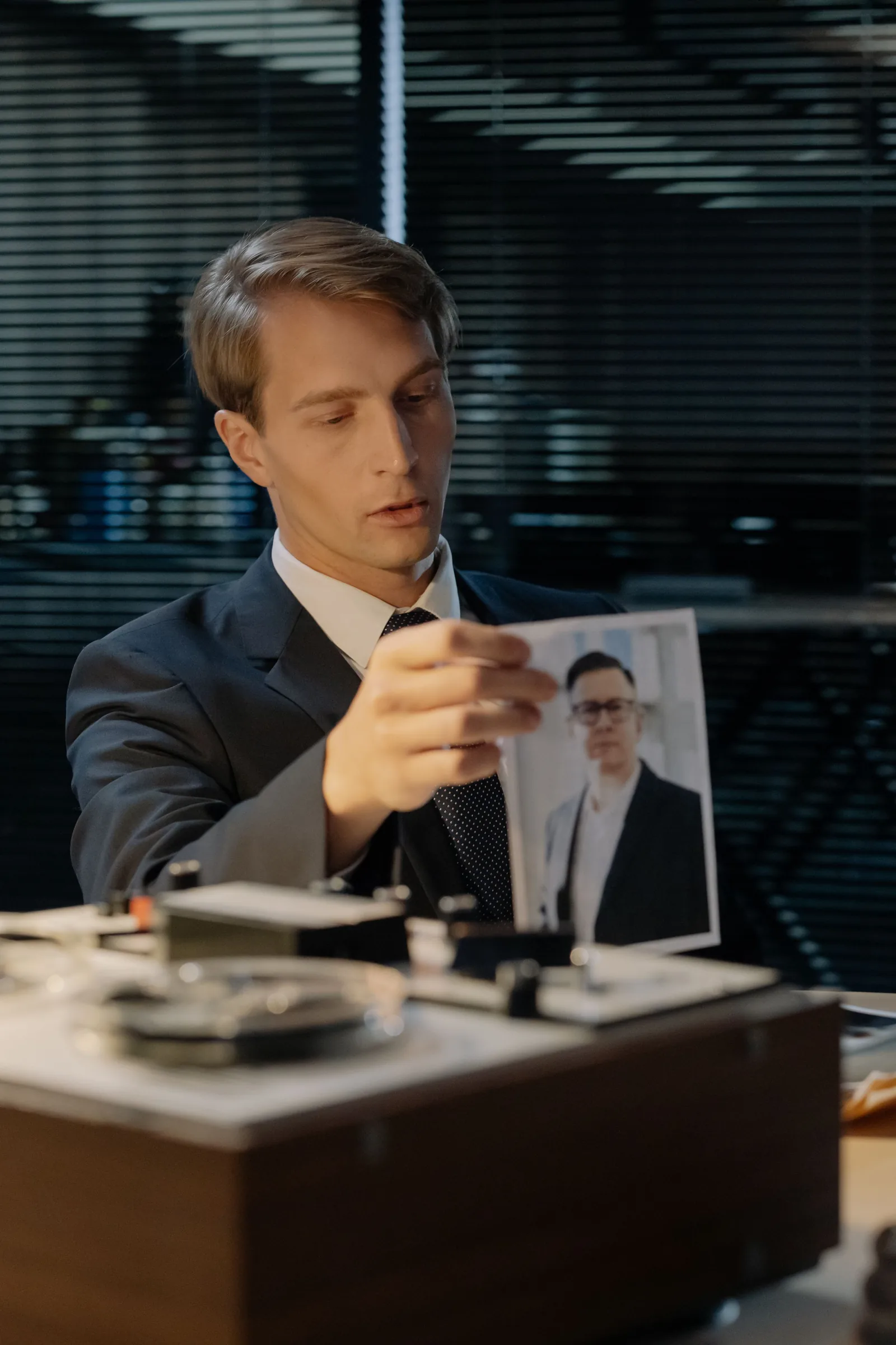 Two professionals in business attire shaking hands across a desk with a gavel and laptop.