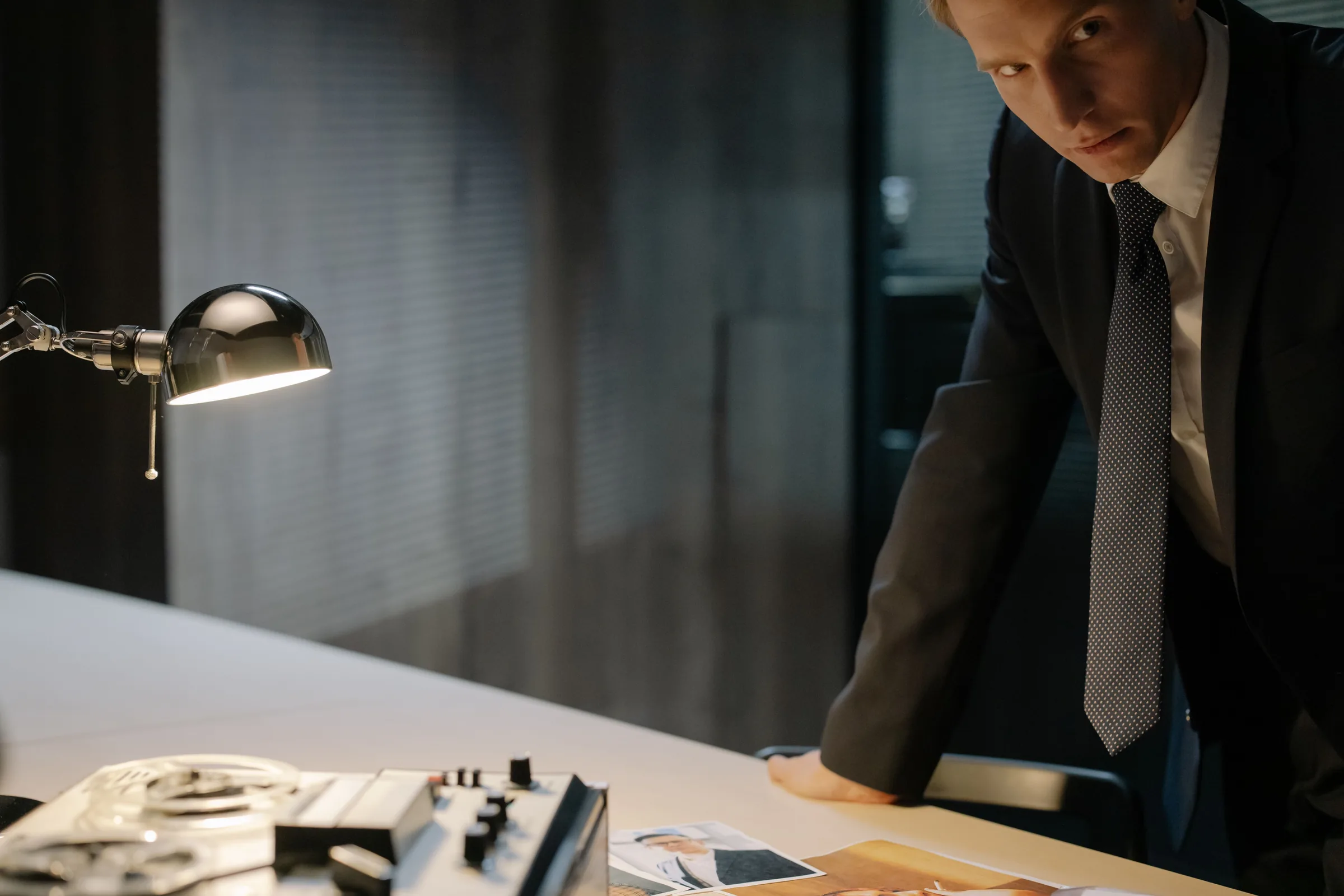 Man in white shirt reviews documents on tablet at wooden desk during business meeting.